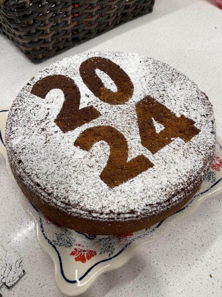 round brown cake dusted with powdered sugar outlining 2024