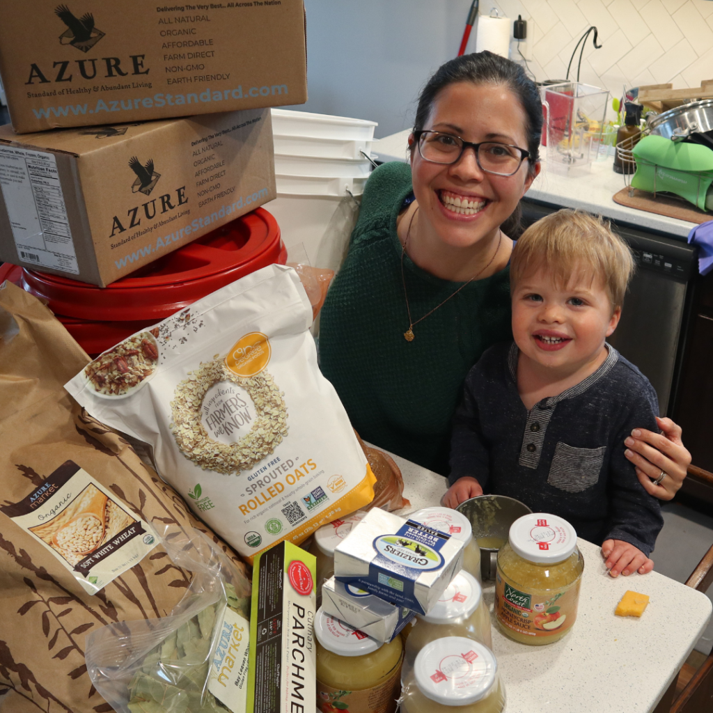 mother and toddler son posing with boxes and bags of food from Azure Standard