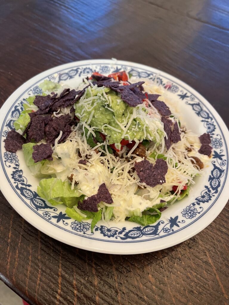 taco salad topped with shredded cheese and blue corn chips